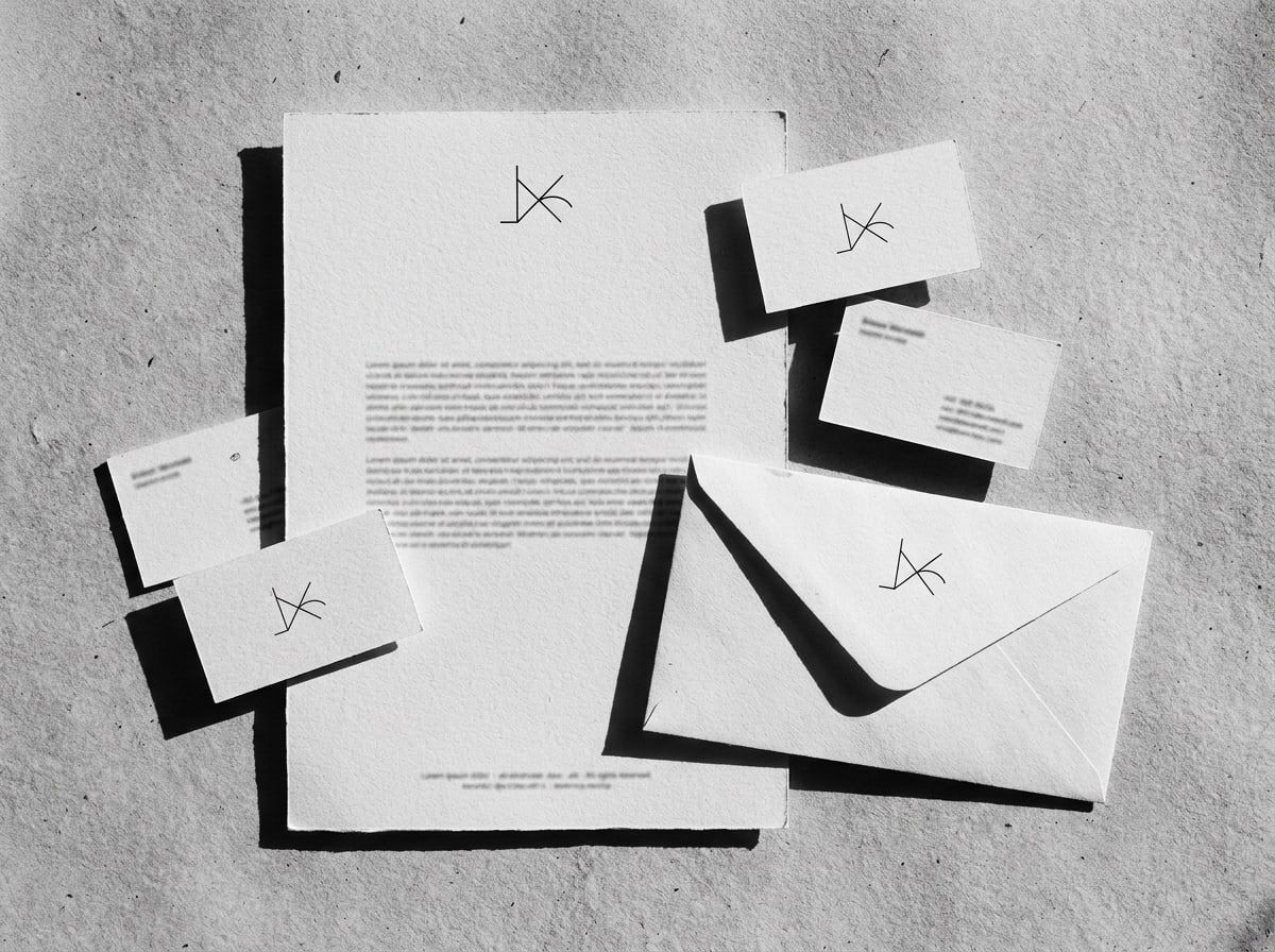 Letterhead, business cards, and envelope with a minimal brand mark on concrete
