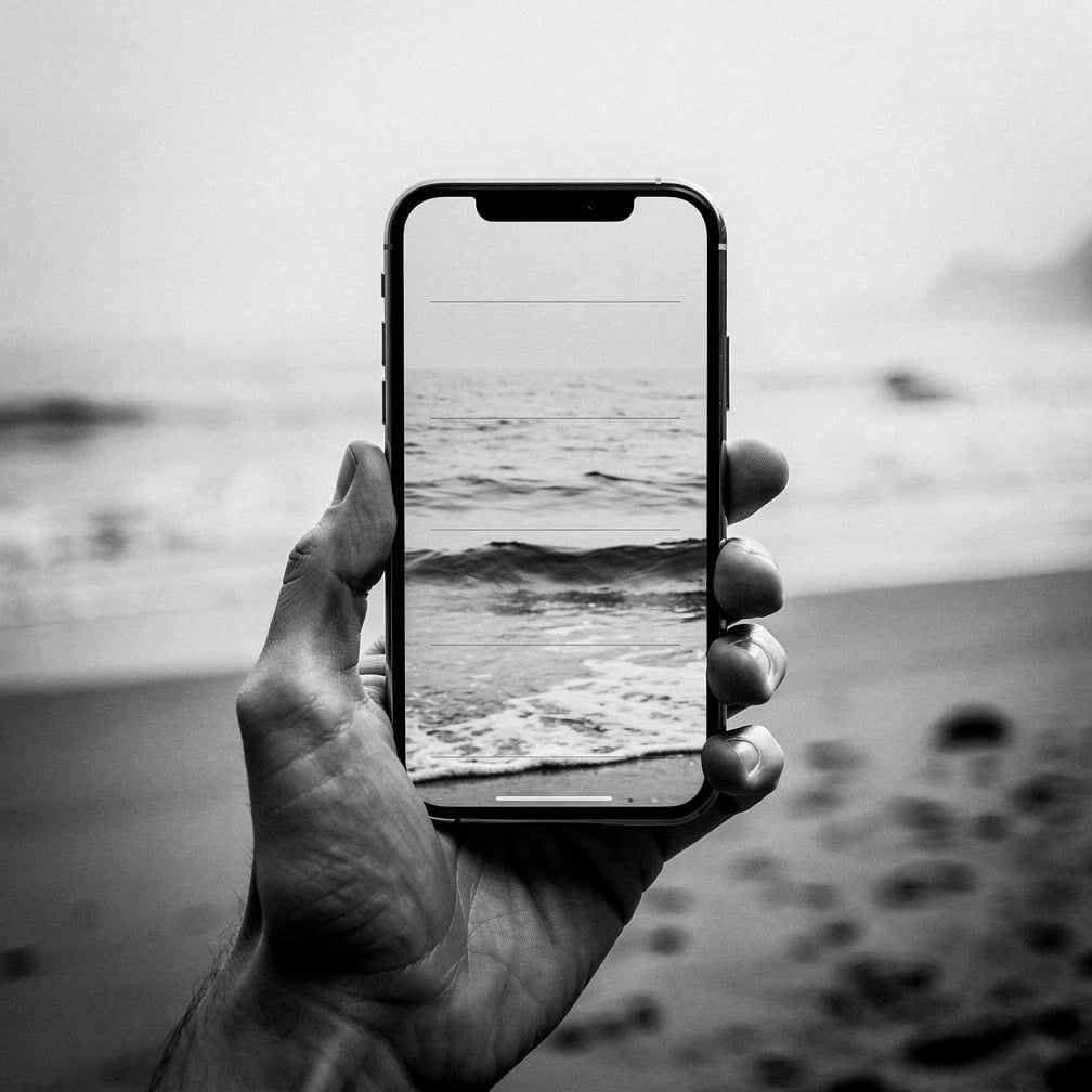 Hand holding a phone at the beach with an ocean photo on screen